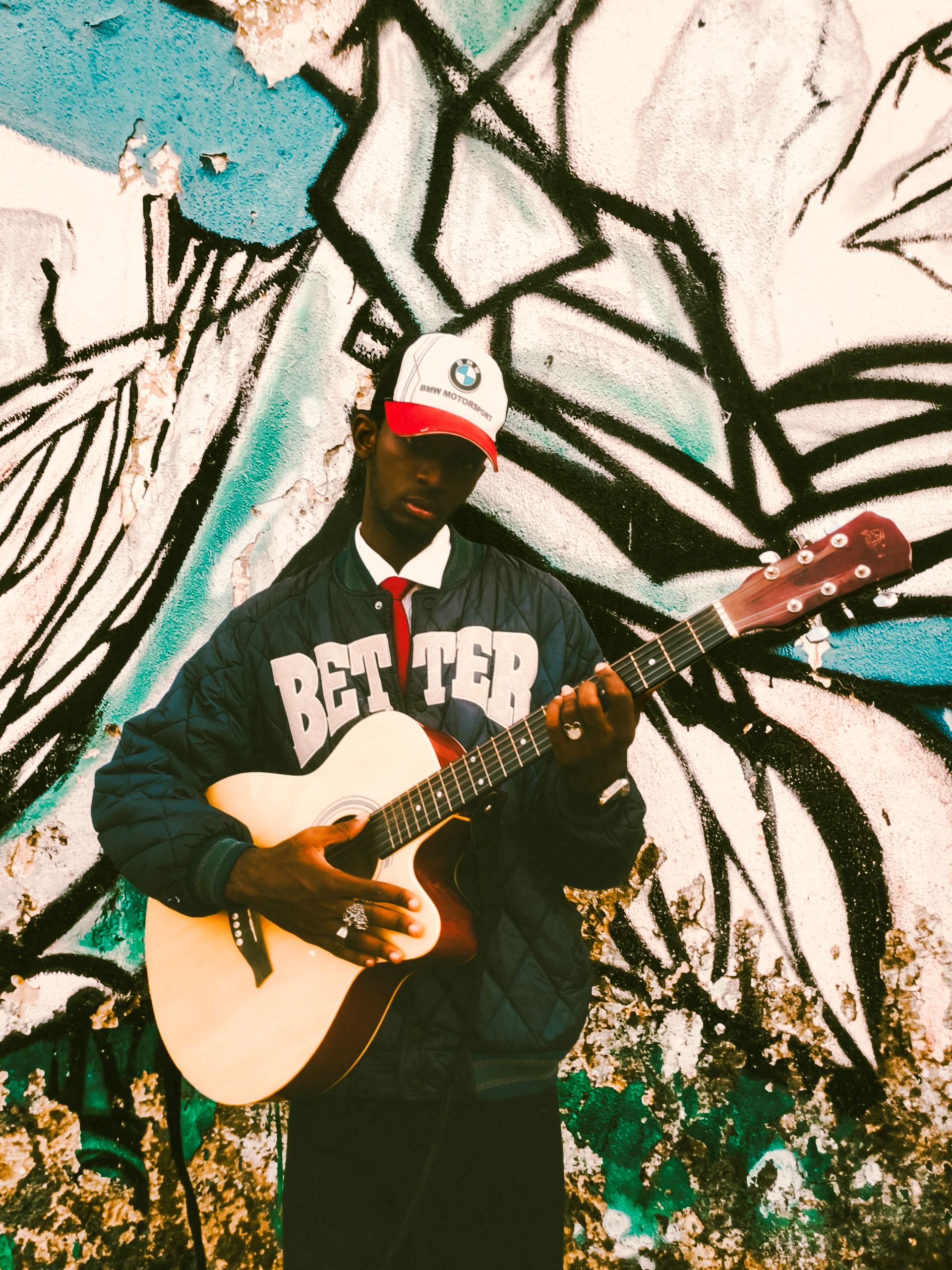 An artist with an acoustic guitar against a painted wall